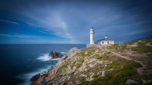 Lighthouse by sea against sky