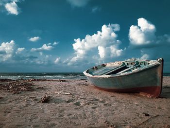 Boat moored on beach against sky