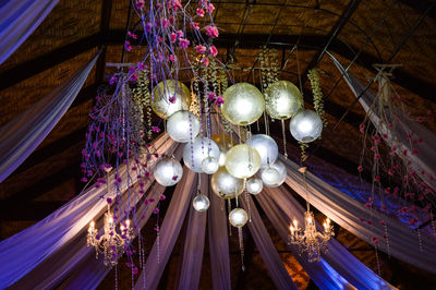 Low angle view of illuminated light bulbs hanging from ceiling