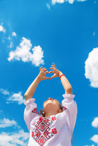 Rear view of woman with arms raised against sky