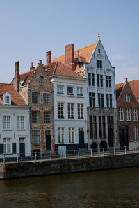 Buildings by river against sky, brugge, belgium