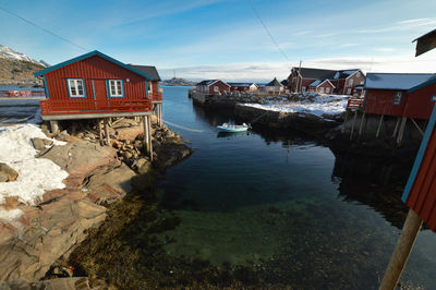 Houses by lake and buildings against sky