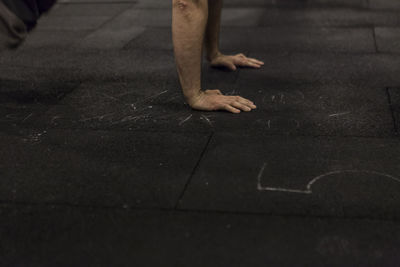 Cropped hands of man doing push-ups on floor at gym