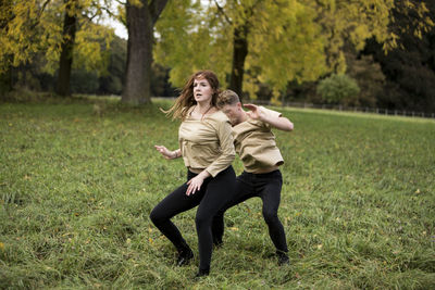 Young couple dancing on grassy field at park