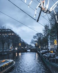 Canal amidst illuminated city against sky