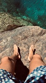 Low section of man relaxing on rock