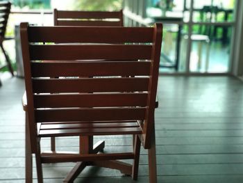 Empty chairs and table against window