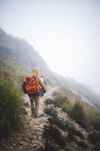 Two hikers walking down through path during foggy day