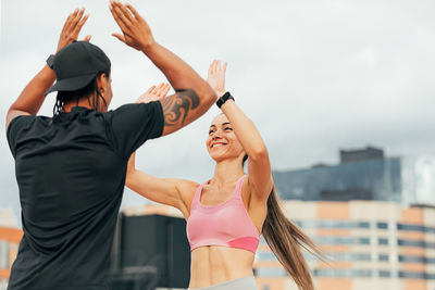 Rear view of woman with arms raised against sky