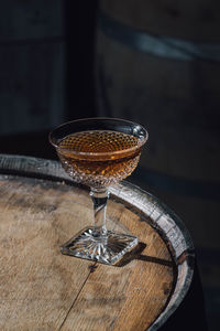 Whiskey cocktail in vintage hobnail glass atop wood bourbon barrel