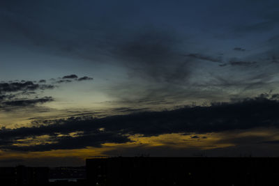 Low angle view of dramatic sky over silhouette landscape