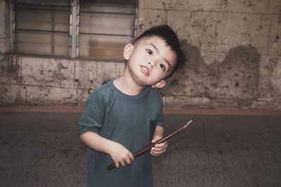 Portrait of boy holding candle while standing against wall