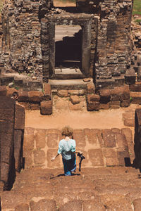 Rear view of woman moving down on steps at temple