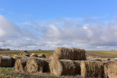 Hay bales on field against sky