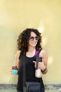 Mixed race woman smiling while drinking mate outdoors.