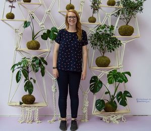 Portrait of a smiling young woman standing against potted plants