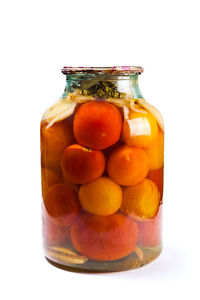 Close-up of fruits in jar against white background