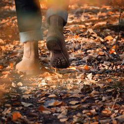 Low section of person standing by autumn leaves