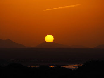 Scenic view of silhouette mountains against orange sky