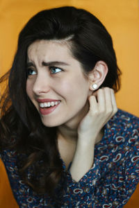 Portrait of a smiling young woman orange background emotional laughing