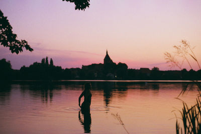 Silhouette woman standing in river during sunset