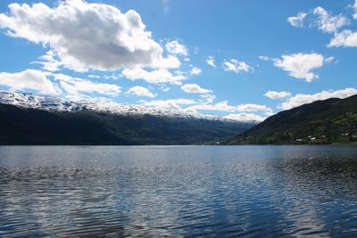 Scenic view of lake by mountains against sky