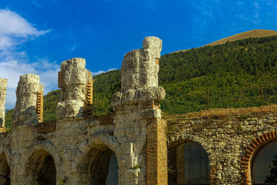 Detail of the ancient roman theater in the background the ingino mountain full of green fir trees