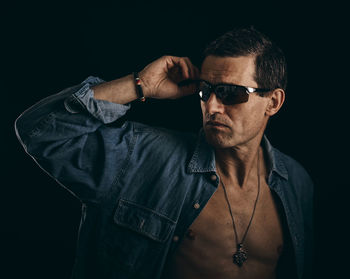 Portrait of man wearing sunglasses against black background