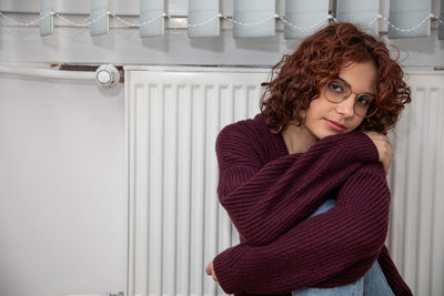 Portrait of young woman standing against wall