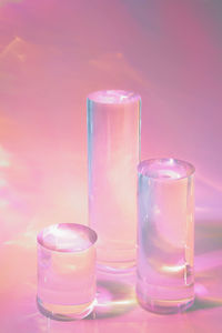 Three clear glass cylinder podiums on pastel pink background