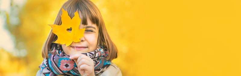 Portrait of young woman against yellow background