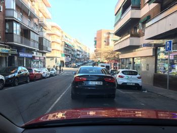 Cars on road by buildings in city