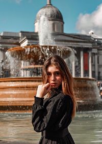 Portrait of a beautiful young woman standing against water