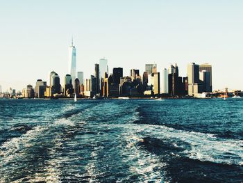 Cityscape by river against clear sky