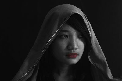 Close-up of young woman against black background