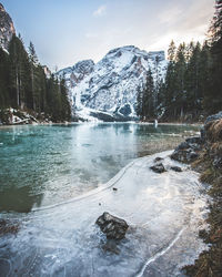 Scenic view of lake by snowcapped mountains against sky during winter