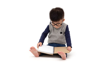 Boy holding book against white background