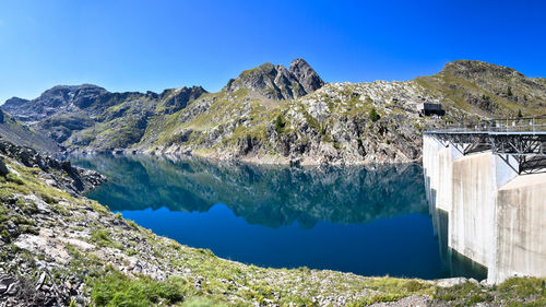 Scenic view of lake and mountains against clear blue sky