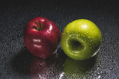 Close-up of wet apple on table against black background