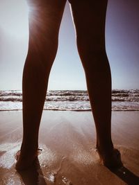 Low section of woman standing at beach against clear sky