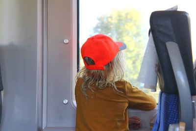 Rear view of girl looking through window of train