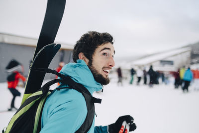 Bearded man wearing backpack while looking away at ski resort