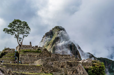 Low angle view of man standing on rock against sky