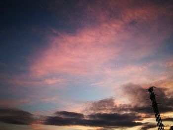 Low angle view of silhouette electricity pylon against sky during sunset