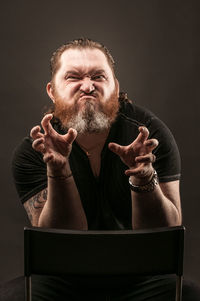 Portrait of man sitting against black background