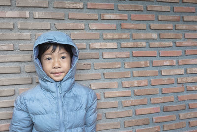 Portrait of boy standing against brick wall