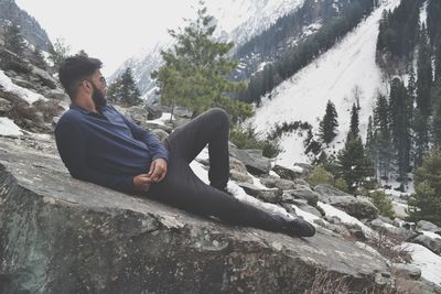 Man leaning on rock during winter