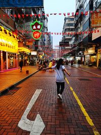 Rear view of people walking on street in city