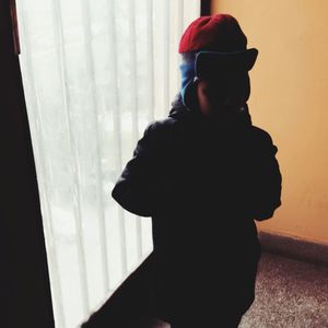 Side view of man standing by window at home