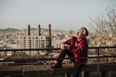 Man standing by railing against sky